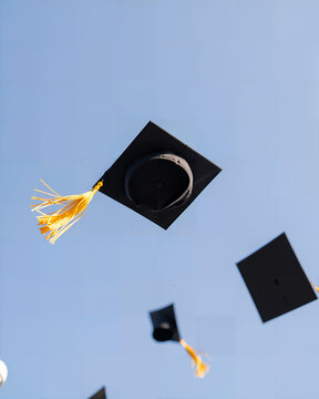 Graduation caps being thrown in celebration against blue sky