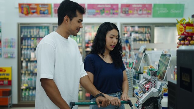 Young couple using self checkout kiosk in a convenience store, making purchasing process faster and more efficient
