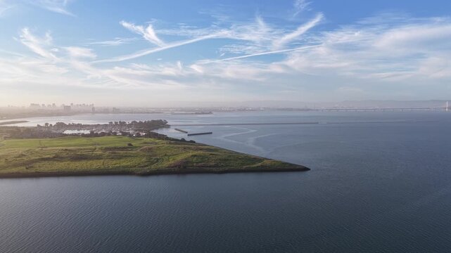 Morning aerial footage showing Cesar Chavez Park and Albany Beach in Berkeley, California, with the San Francisco skyline visible in the hazy distance across the bay under a blue sky