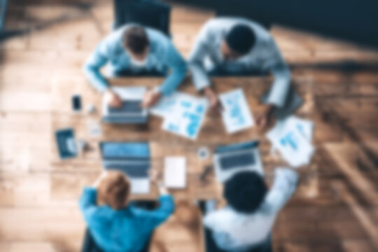 Blurred Diverse team collaborating on business project with laptops and documents