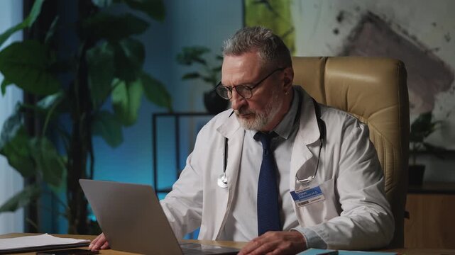 Tired male doctor closing laptop in office, feeling stressed about work overload