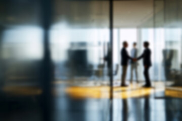 Obraz premium Blurred Businessmen shaking hands in modern office with glass walls