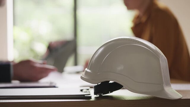 Construction manager and female client discussing architectural papers in office