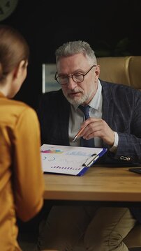 Life insurance agent talking with female client in office, discussing statistics