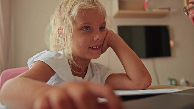 Preschool girl learns with her mother using digital resources on a laptop. Early education and school preparation at home