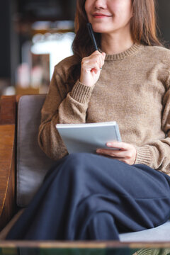 Vertical closeup image of a woman thinking and writing on a notebook
