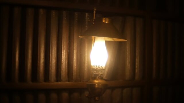 A warm, glowing lamp casts soft light on rows of vintage books in a cozy, atmospheric library or study space perfect for literary scenes or serene reading environments
