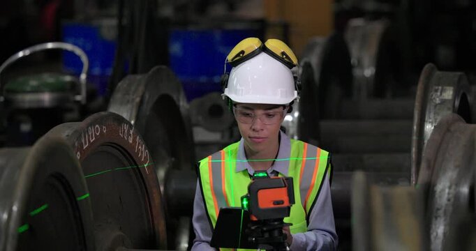 A locomotive engineer in a factory setting uses a laser measuring tool, demonstrating the precision and technical skills required in industrial engineering and construction environments.
