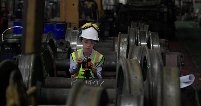 A locomotive engineer in a factory setting uses a laser measuring tool, demonstrating the precision and technical skills required in industrial engineering and construction environments.
