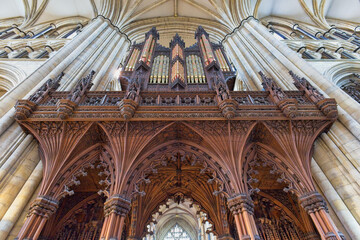 Ornate wooden carvings frame a grand organ in a cathedral's interior, reaching towards a ribbed, vaulted ceiling in Beverley Minster - Yorkshire - Great Britain © Robert
