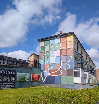 Vibrant geometric mural featuring a white dove, symbolising peace and unity, painted on the side of a residential building in the Bogside area of Derry. 