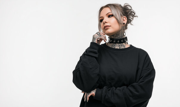 Plus size female model wearing a blank black sweatshirt on a white background. Emo, alternative, punk, goth, tattoos, unconventional, casual pose, e-commerce style photography. Perfect for mockup.