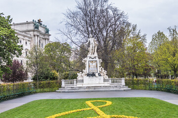 Fototapeta premium Statue of Wolfgang Amadeus Mozart with a treble clef flower bed in Burggarten, Vienna.