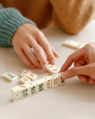 Fototapeta premium Close-up hands arranging mahjong tiles during a lesson for game tutorial and tabletop background banner showing traditional mahjong play