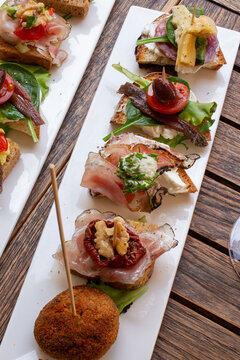 Venetian cicchetti tray with anchovies cured ham mushrooms and meatball on rustic wooden table