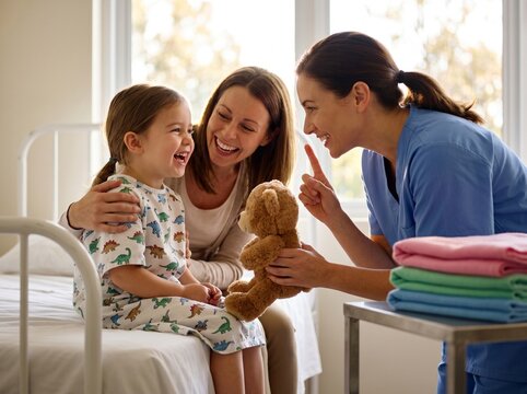 Nurse making a playful shushing gesture to a smiling girl in her pediatric hospital room