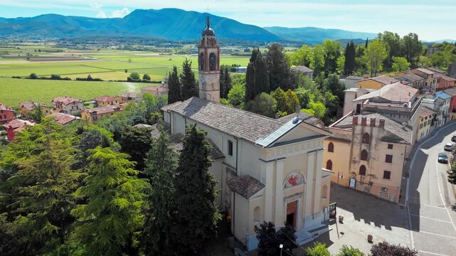 Historic church building and small town center with surrounding countryside and farmland in Costermano sul Garda, Italy, aerial view