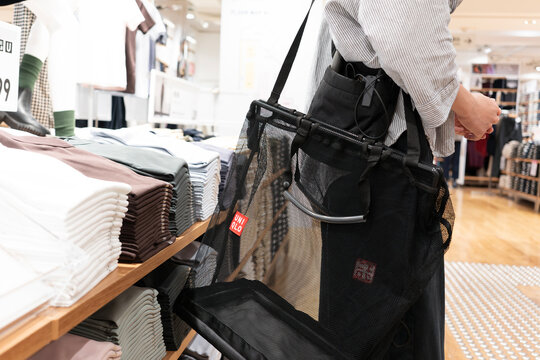 Uniqlo staff member with mesh shopping bag in store