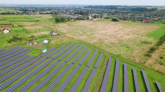 Aerial view of solar panel farm integrated into countryside farmland. Renewable electricity infrastructure scene suitable for energy transition and sustainable future visuals