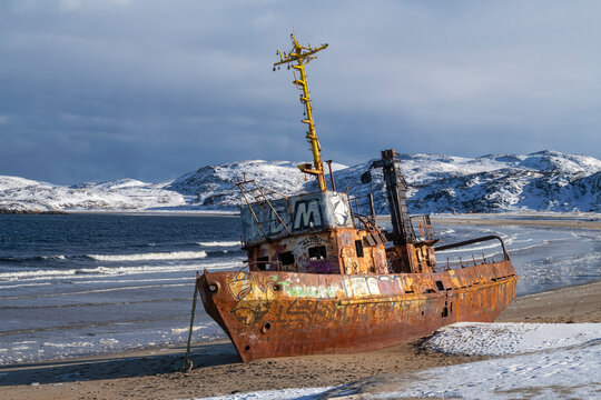 The old fishing trawler on the shore of Lodeynaya Guba Bay on a March day. Murmansk Region