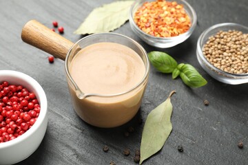Naklejka premium Tasty turkey gravy and spices on dark textured table, closeup