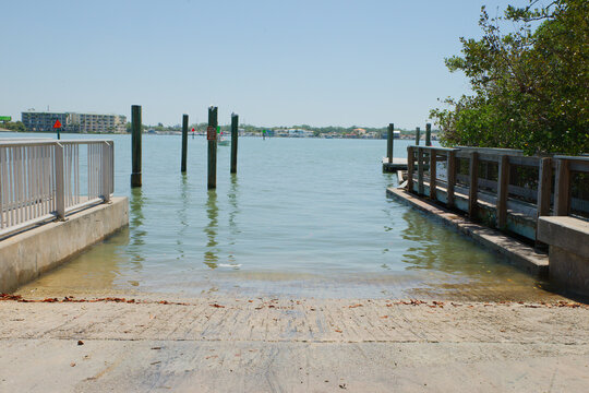 Boat Launch Ramp and Wooden Dock on Calm Waterfront With Pilings and Distant Marina At War Veterans Memorial Park Saint Petersburg, FL.Calm coastal water with pilings, mangroves and distant marina bui
