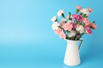 Obraz premium Beautiful carnation flowers in vase on light blue background, space for text