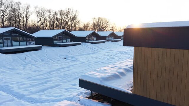 Modern wooden frame house with large glass facade in snowy landscape at sunset, showcasing contemporary architecture, energy efficient design and winter residential lifestyle
