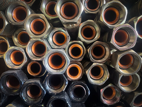 Top view abstract pattern of high-pressure hydraulic hose fittings with orange internal seals and silver hexagonal metal nuts