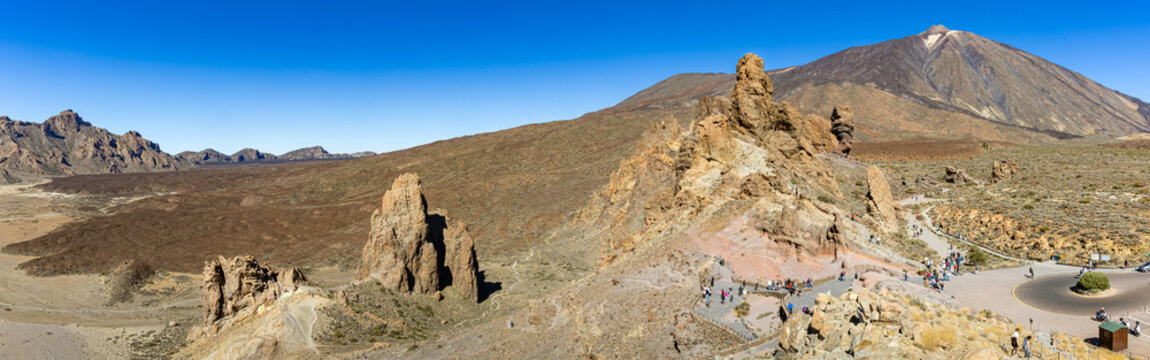 A wide panoramic view of the volcanic landscape with mount Teide at Teide National Park, showing the rugged rock formations of the Llano de Ucanca under a clear blue sky