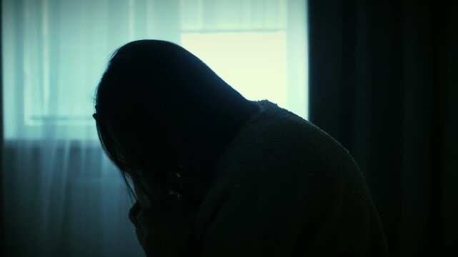 Young woman sitting alone near a window, slowly touching her face in a moment of deep thought. Scene of overthinking, emotional fatigue and inner reflection, soft natural light, calm cinematic