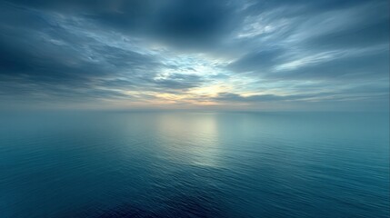 Fototapeta premium Serene Ocean Horizon Under Dramatic Cloudy Sky at Dawn with Soft Blue Tones and Gentle Reflections on Water Surface