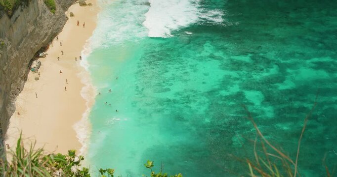 People relax on sandy shore and swim in turquoise sea at Diamond Beach Nusa Penida Indonesia