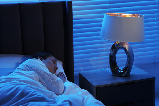 Woman sleeping with illuminated night lamp at home
