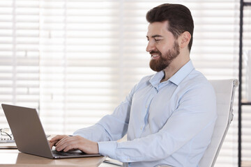 Fototapeta premium Handsome businessman working on laptop at wooden desk in office