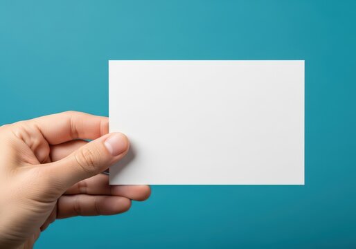 A hand holding a blank business card against a light blue background