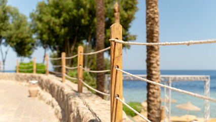 Naklejka premium Sunlit path winds past rope fencing