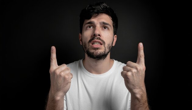 Man in white t-shirt pointing upwards with both hands.