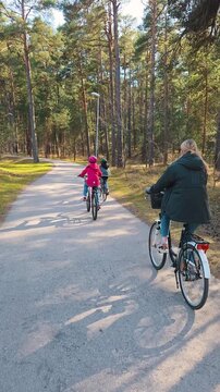 Family with children riding bicycles on a forest bike path on a sunny spring day