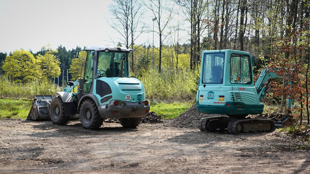 Ein t&uuml;rkisfarbener Weycor Radlader Modell AR 420 und ein  t&uuml;rkisfarbener Takeuchi Minibagger Modell TB 228 an einem Waldrand