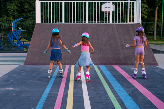 Girls roller skating in a skate park in the late summer evening. Group roller skating lessons