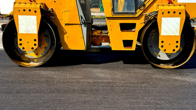 Yellow roller compacts fresh asphalt