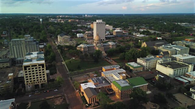 Drone approach to Mississippi State Capitol with government buildings streets and downtown skyline under cloudy evening sky Jackson Mississippi USA