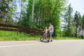 Obraz premium Father teaching his daughter how to ride a bicycle in forest