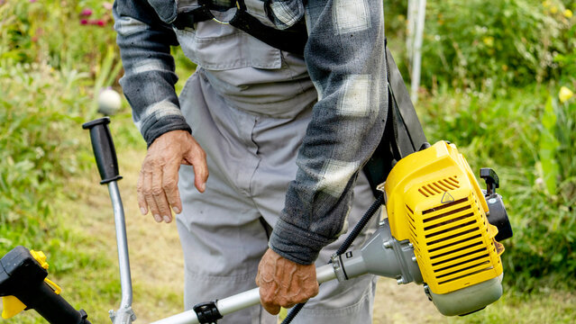 Man grips a yellow-powered brush cutter