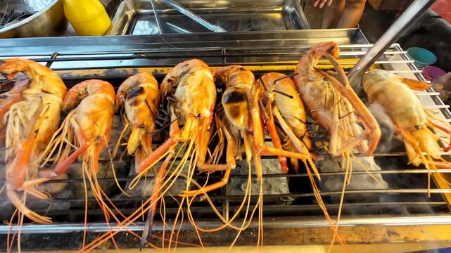 A street food market in a rural Thai town sells medium-sized grilled river prawns to tourists.