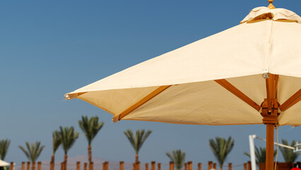 Beige umbrella stands tall on sandy beach © I