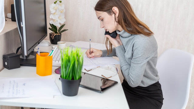 Busy occupied business woman working from home, call at mobile phone, checking emails, reading text messages, making an appointment, using modern technology in home office.