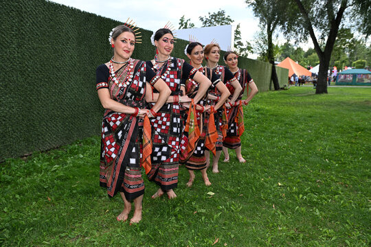 Five female dancers in colorful costumes dancing Indian dances in the park