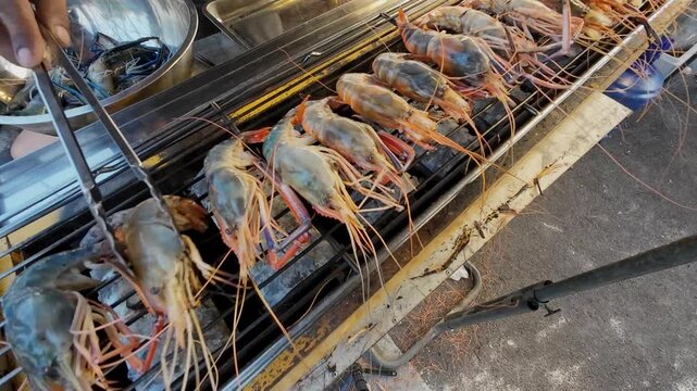 A street food market in a rural Thai town sells medium-sized grilled river prawns to tourists.